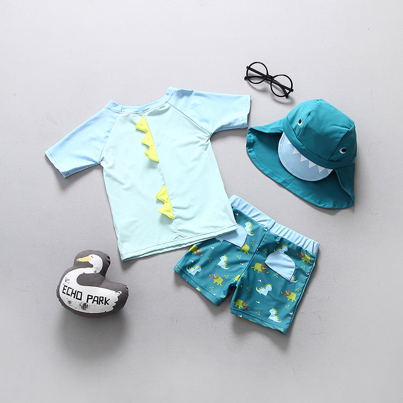 Boys dinosaur swimming suit featuring a blue top with scales and patterned shorts, with a matching hat and float.