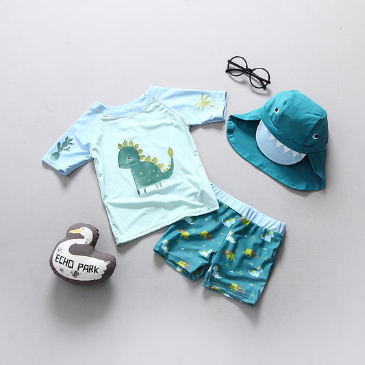 Boys dinosaur swimming suit featuring a dinosaur graphic, paired with shorts, sunglasses, and a matching hat.