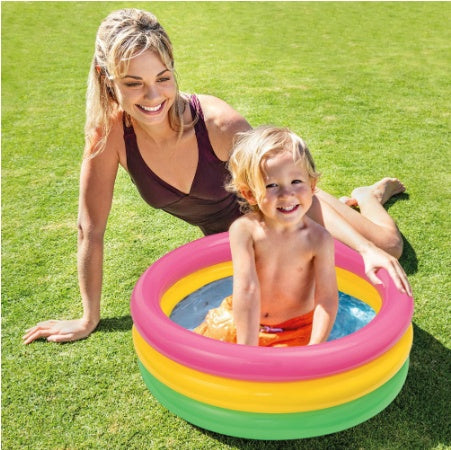 Kids inflatable paddling pool shown outdoors on grass with an adult and child